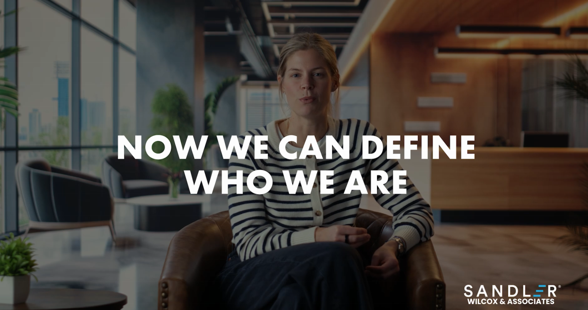 woman in an office setting with a phrase that reads "now we can define who we are"